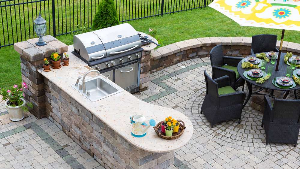 Outdoor kitchen and dining table on a paved patio