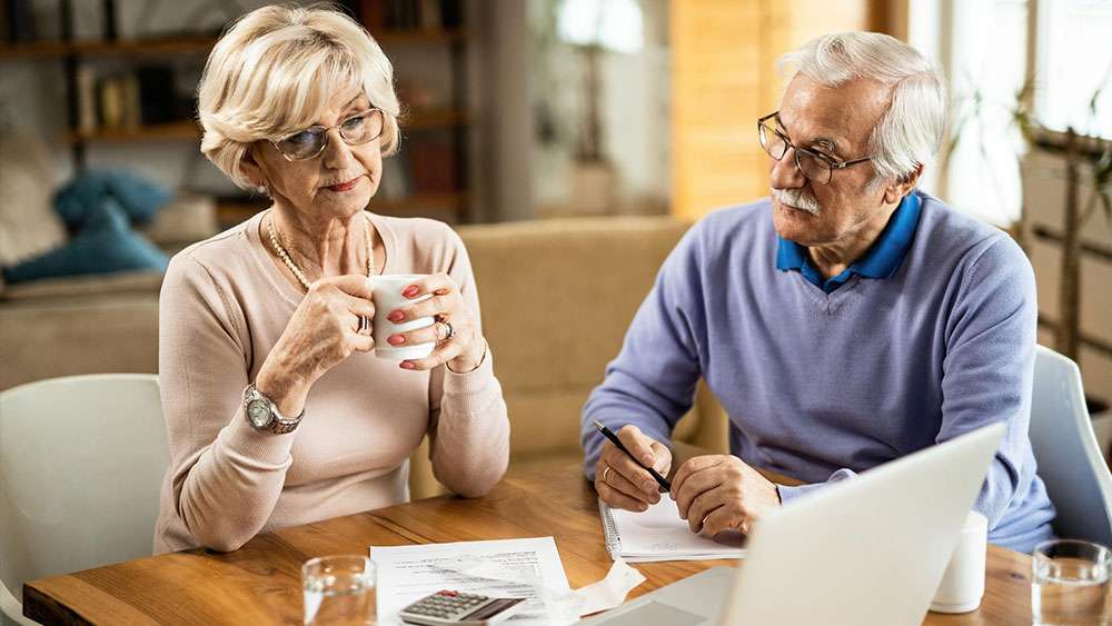 Senior couple analyzing their home budget and using a computer and calculator